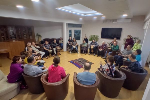 Mieszkańcy uderzają w bębny siedząc.