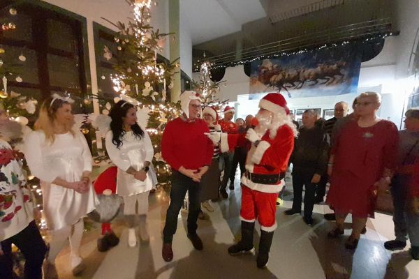 Przybyli Goście w strojach Mikołajów i śnieżynek wraz z mieszkańcami na holu domu.
