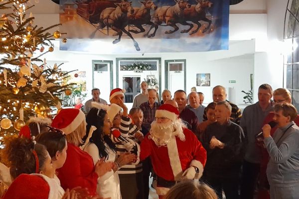 Przybyli Goście w strojach Mikołajów wraz z mieszkańcami na holu domu.
