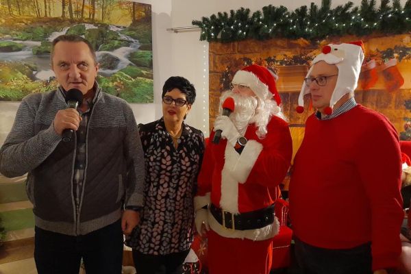 Mieszkaniec mówi do mikrofonu a obok stoi Pani Dyrektor i dwa mikołaje.