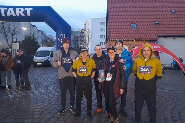 Czworo mieszkańców stoi w zdjęciu grupowym wraz z dwojgiem prowadzących biegi.