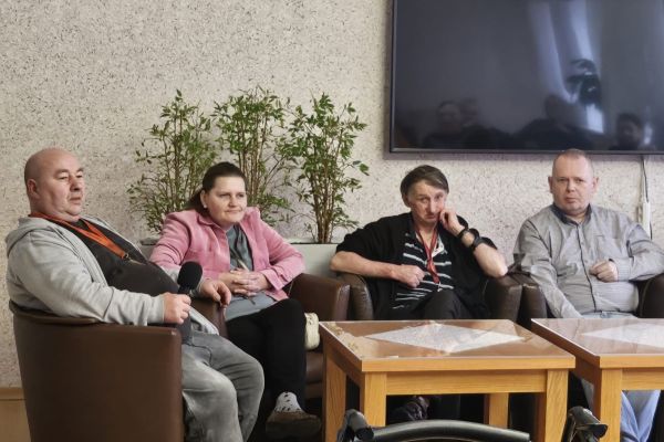 Mieszkańcy siedzą w fotelach i rozmawiają.