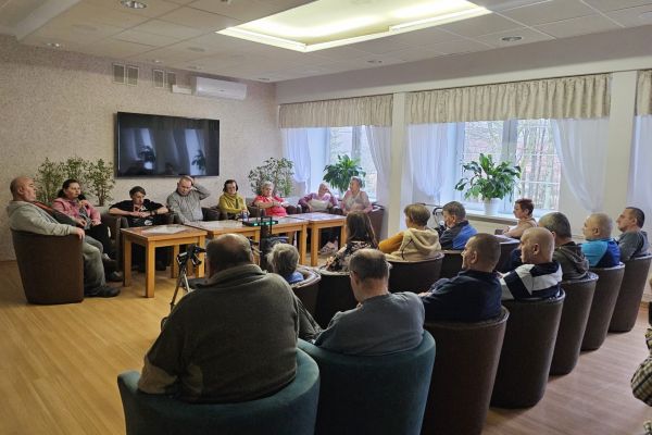 Mieszkańcy siedzą w fdotelach i rozmawiają.