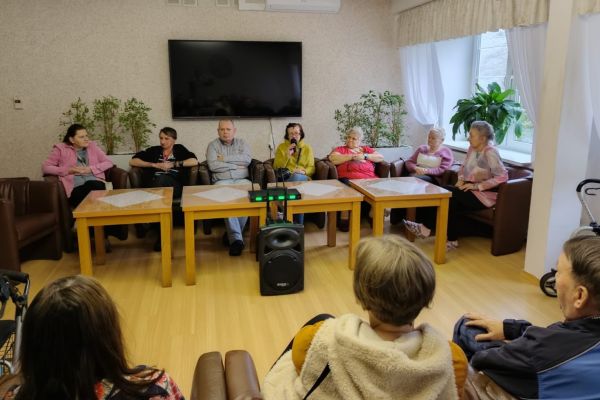 Mieszkańcy siedzą w fotelach i rozmawiają.