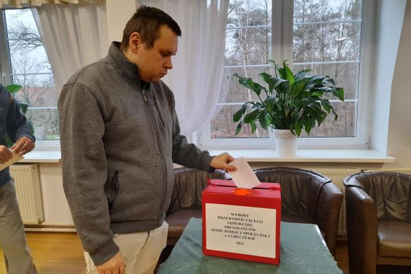 Mieszkaniec wrzyca kartkę do urny.