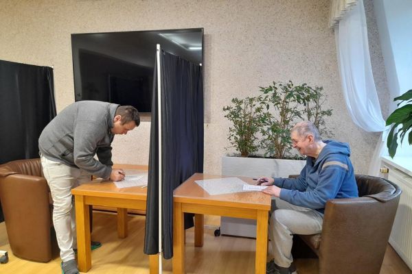 Mieszkańcy wrzucaja kartkę do urny.