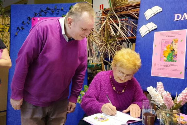 Mieszkaniec stoi i czeka na wpis do książki od poetki.