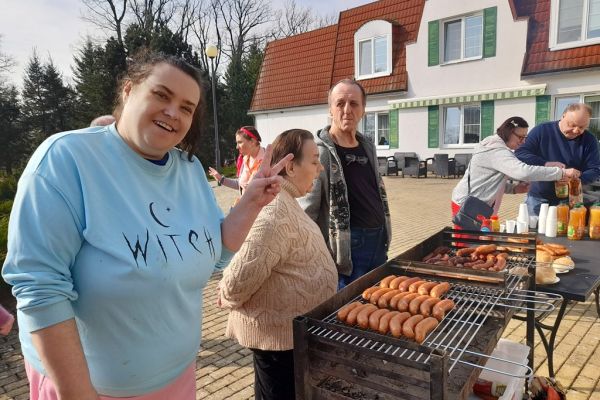 Mieszkańcy stoją przy grillu.