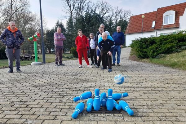 Mieszkańcy graja w kręgle na dworze.