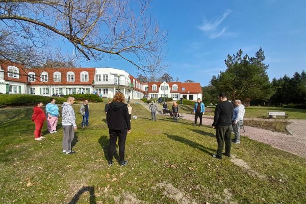 Mieszkańcy ustawieni w duże koło rzucają piłką.