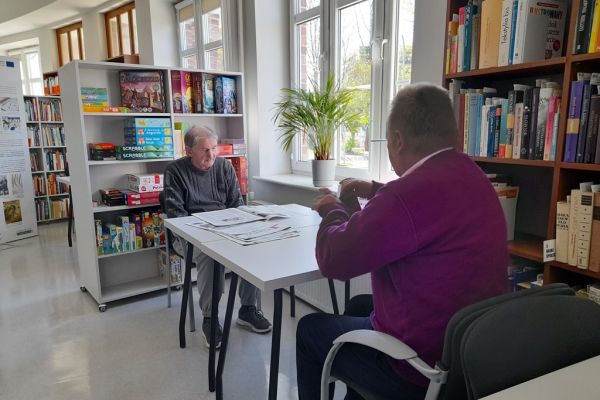 Mieszkańcy czytają przy stolikach w czytelni.