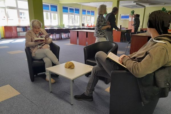 Mieszkańcy czytają przy stolikach w czytelni.