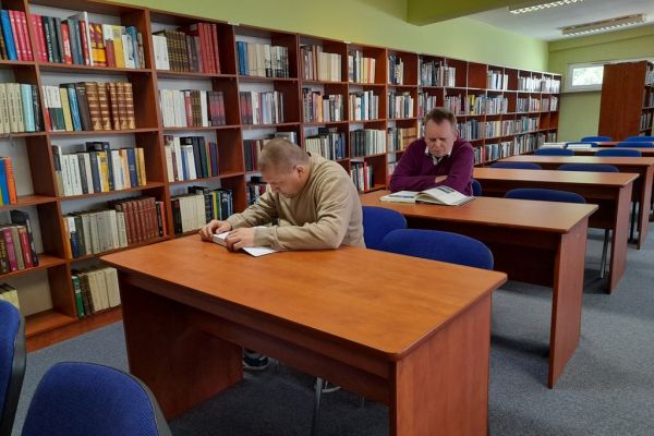 Mieszkańcy czytają przy stolikach w czytelni.