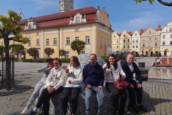 Mieszkańcy siedzą grupą na ozdobnej ławce w Bolesławcu.