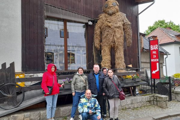 Grupowe zdjęcie mieszkańców przy dużym  słomianym misiu w Szklarskiej Porębie.