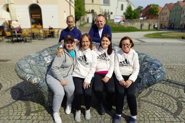 Grupowe zdjęcie siedzący na ozdobnej ławce mieszkańców w Bolesławcu.