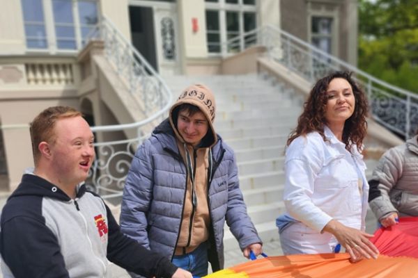 Mieszkaniec wraz z innymi uczestnikami trzyma kolorową chustę.