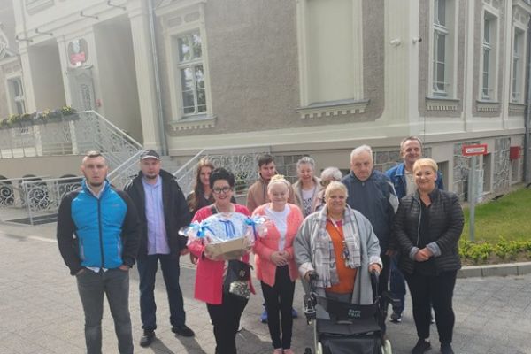 Grupa mieszkańców wraz z Panią Dyrektor trzymającą prezent.