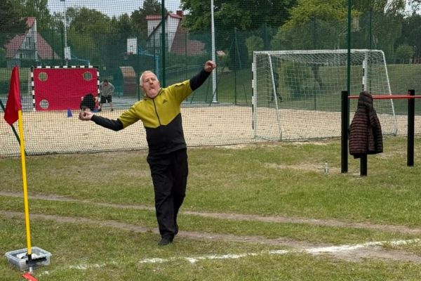 Mieszkaniec rzuca piłką na boisku.