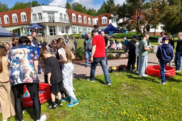 Uczestnicy pikniku łowią sztuczne rybki umieszczone w małych basenach dmuchanych.