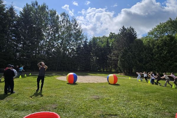 Uczestnicy festynu podczas zabawy z dużymi dmuchanymi piłkami.