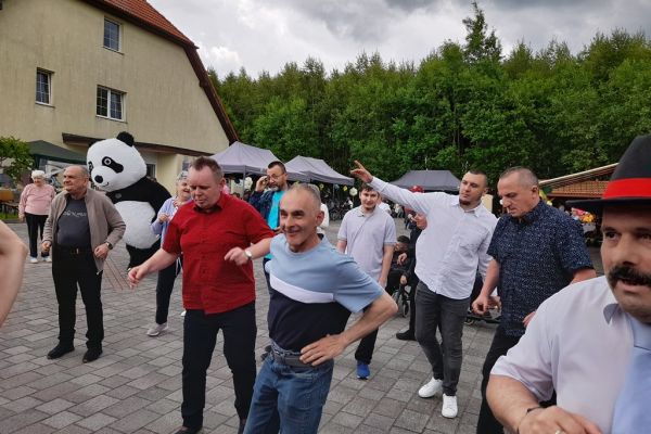 Mieszkańcy tańczą wsród innych uczestników pikniku.