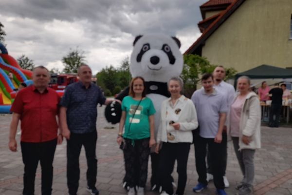 Grupowe zdjęcie z gigantyczna maskotką pandy.