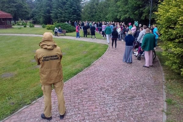 Mieszkańcy podczas szkolenia stoją ustawieni na ścieżkach w terenie wokół domu.