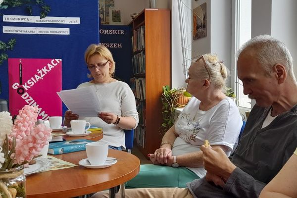 Mieszkańcy siedzą i czytają oraz słuchają tekstów w bibliotece.