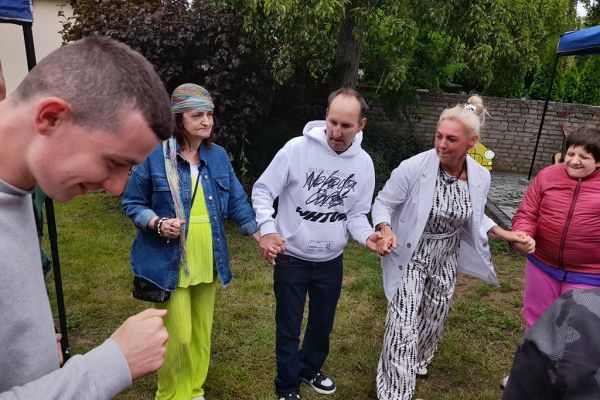 Mieszkańcy wraz z innymi uczestnikami festynu tańczą.