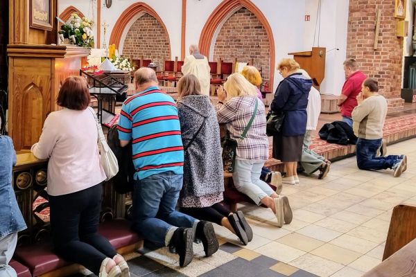 Mieszkańcy modlą się w kościele. Klęczą.