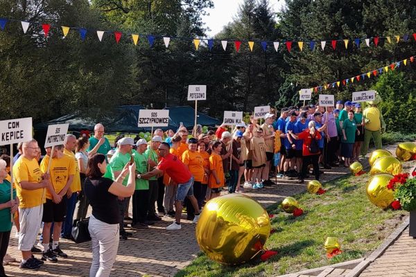Uczestnicy spartakiady stoją w grupach na rozpoczęciu