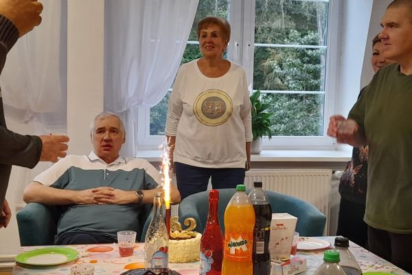 Jubilat siedzi a przed nim tort z racą.