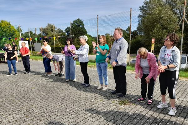 Mieszkańcy podczas zabawy grupowej na pikniku wraz z innymi uczestnikami.