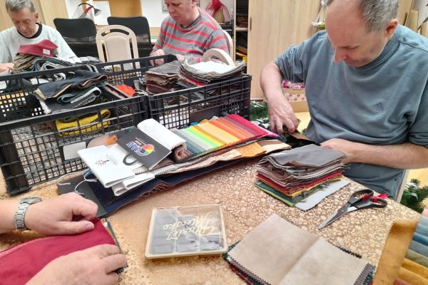 Mieszkańcy wycinaja kwadraty z materiałów.