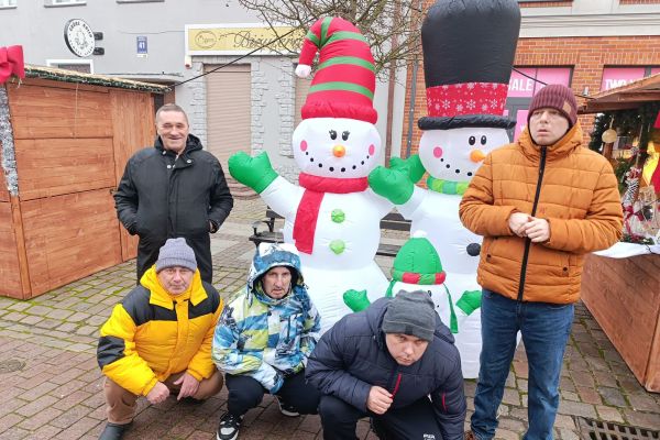 Mieszkańcy stoją przy bałwanie dmuchanym.